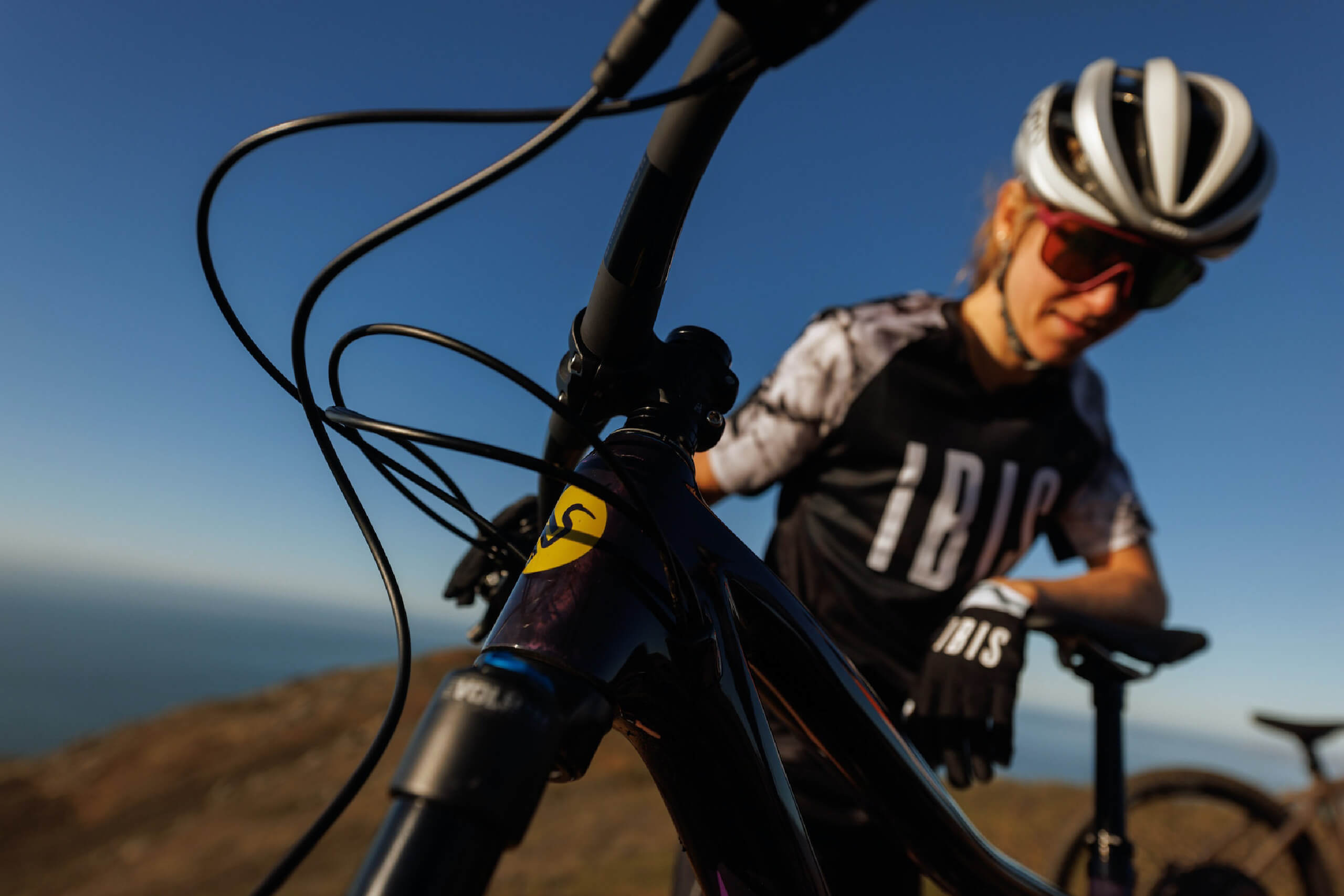 Woman poses with IBIS mountain bike featuring the bird logo and the large IBIS logo on her shirt
