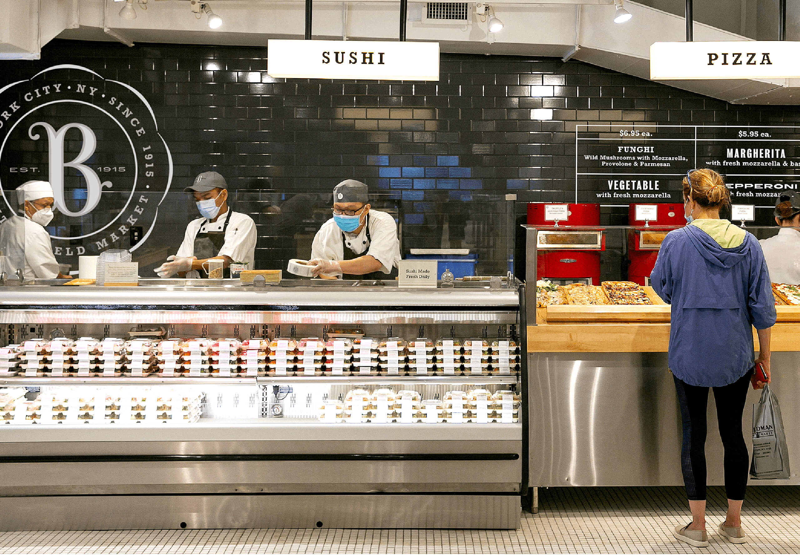 Interior of Butterfield market Madison avenue showing the sushi and pizza counters with dramatic black tile and custom designed signage and graphics
