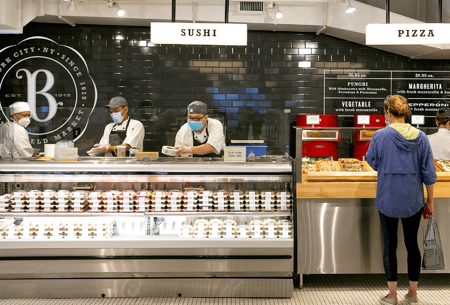Interior of Butterfield market Madison avenue showing the sushi and pizza counters with dramatic black tile and custom designed signage and graphics