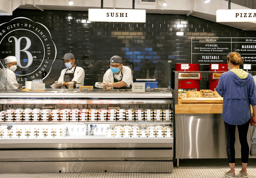 Interior of Butterfield market Madison avenue showing the sushi and pizza counters with dramatic black tile and custom designed signage and graphics